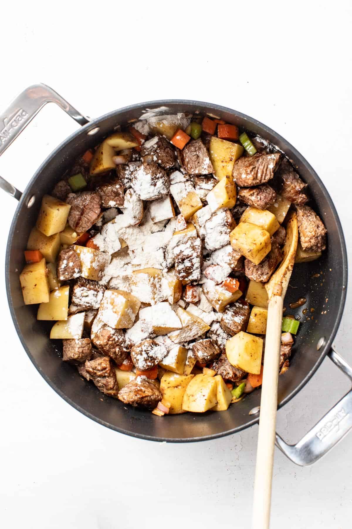 Beef, carrots, potatoes, shallots, and celery with flour in a large simmer pot.