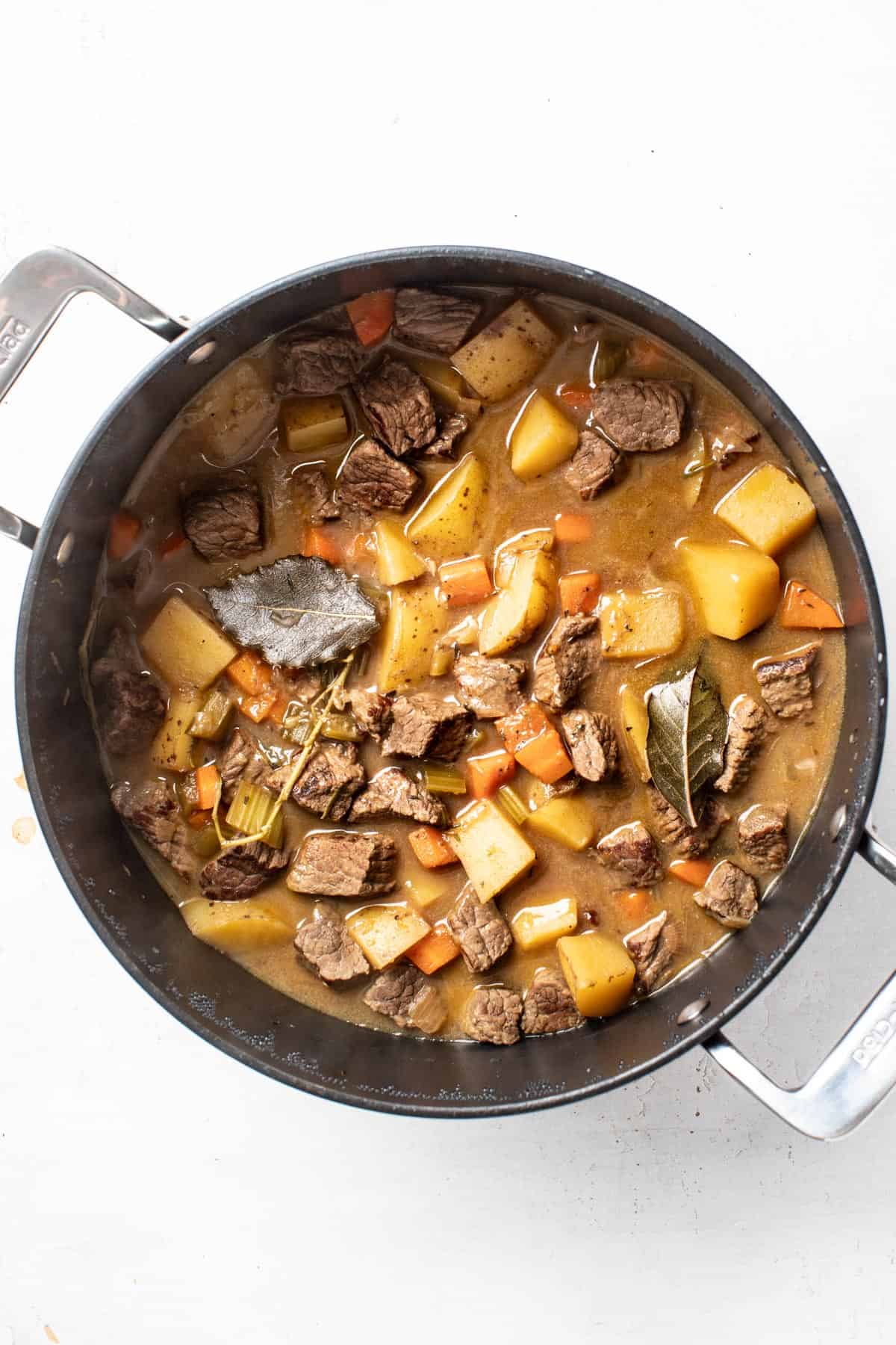 A stovetop beef stew after being simmered with herbs.