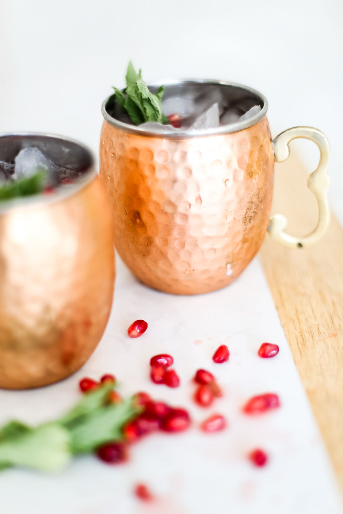 Two copper mugs with pomegranate arils and mint.