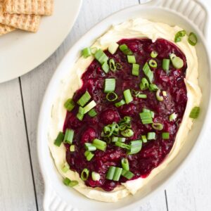 Cranberry Jalapeno Dip on top of a bowl with cream cheese on a white table.