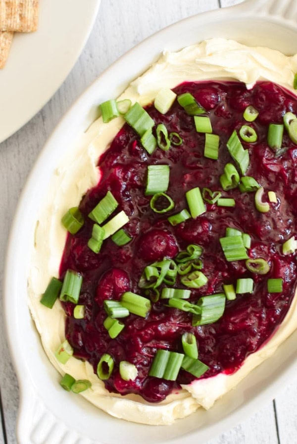 Cranberry Jalapeno Dip on top of a bowl with cream cheese on a white table.