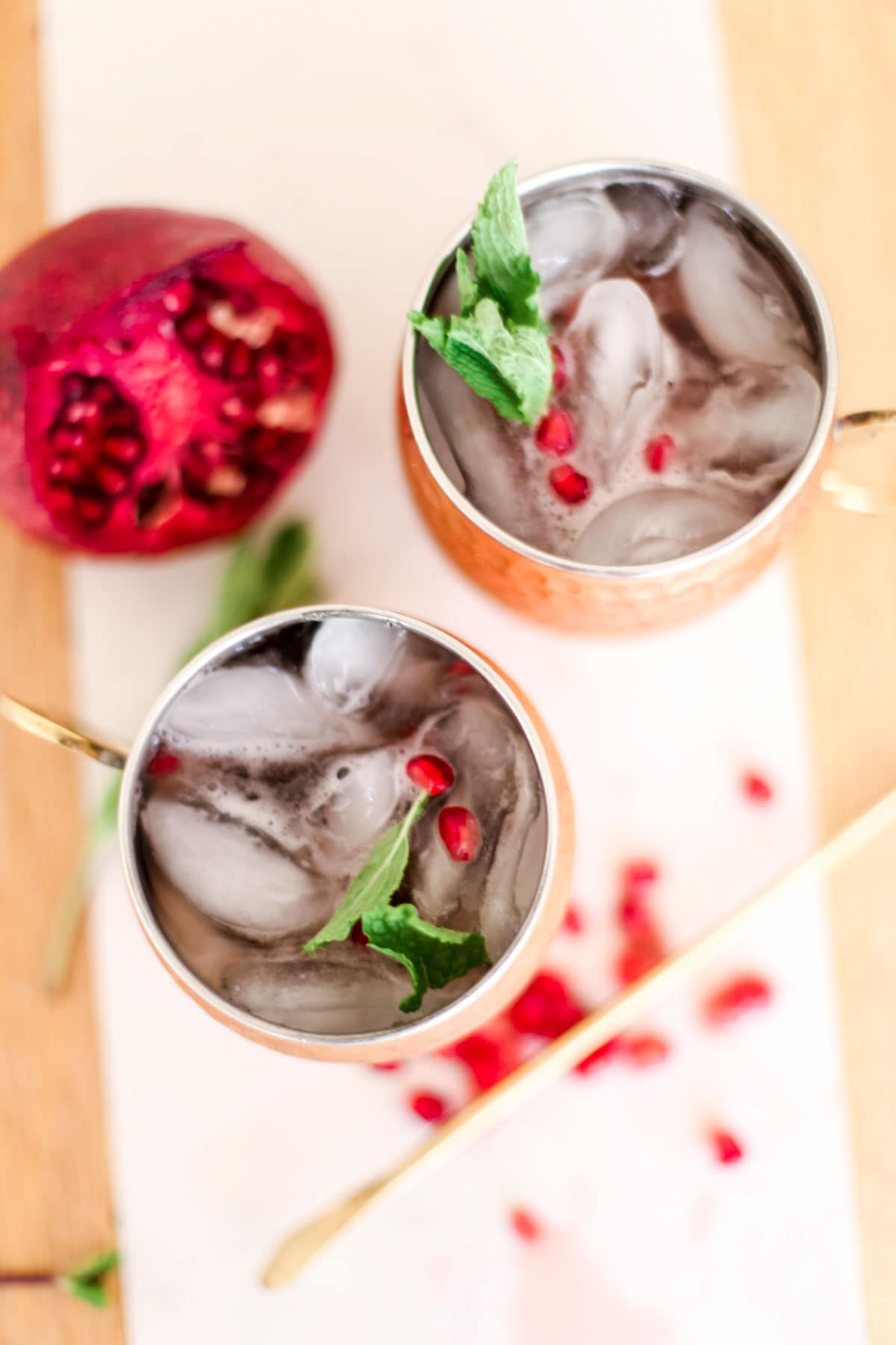 An overhead shot of pomegranate mojito mocktails next to a cocktail stirrer and mint.