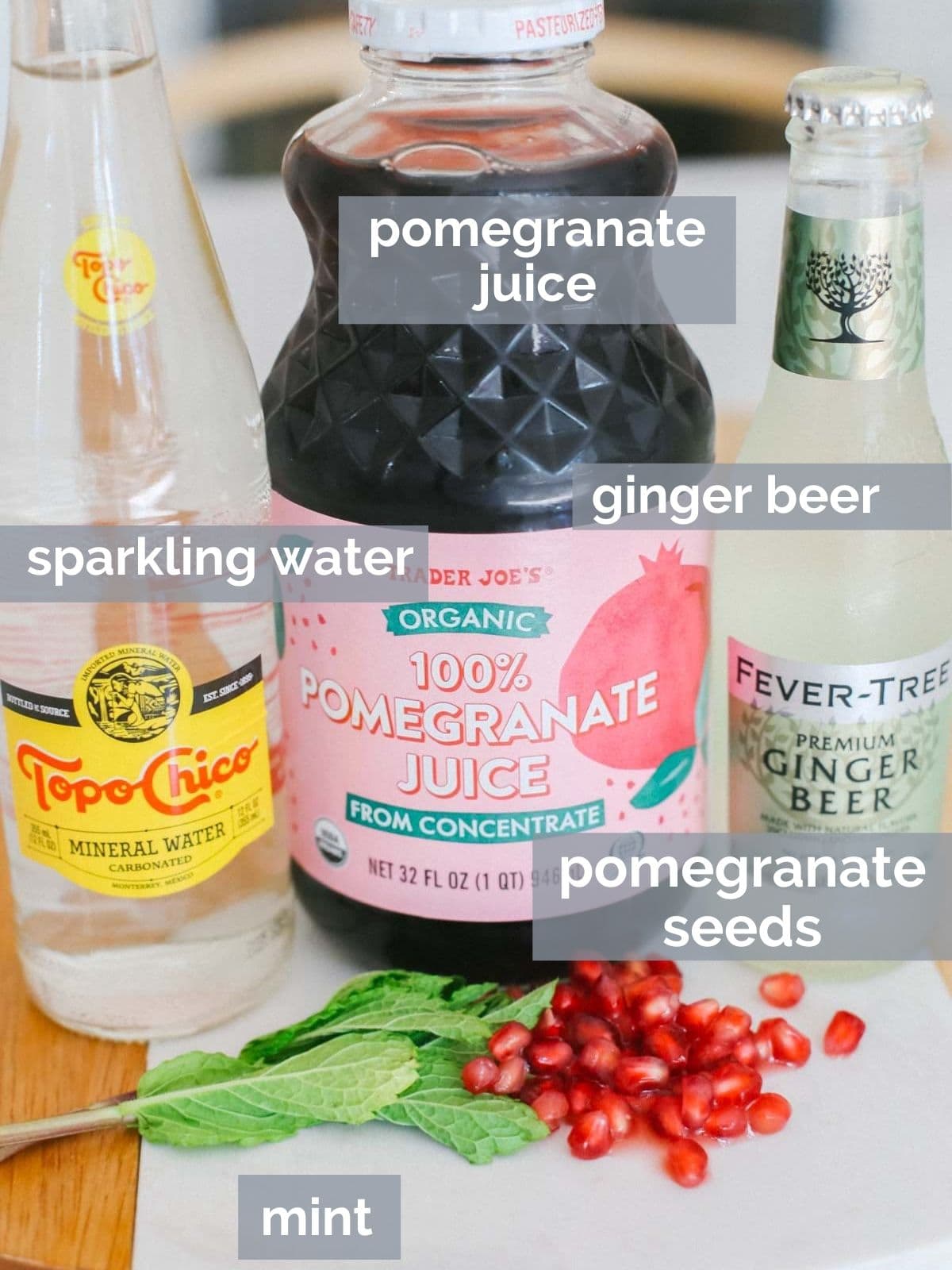 Pomegranate juice, mint, sparkling water, and ginger beer on a table.