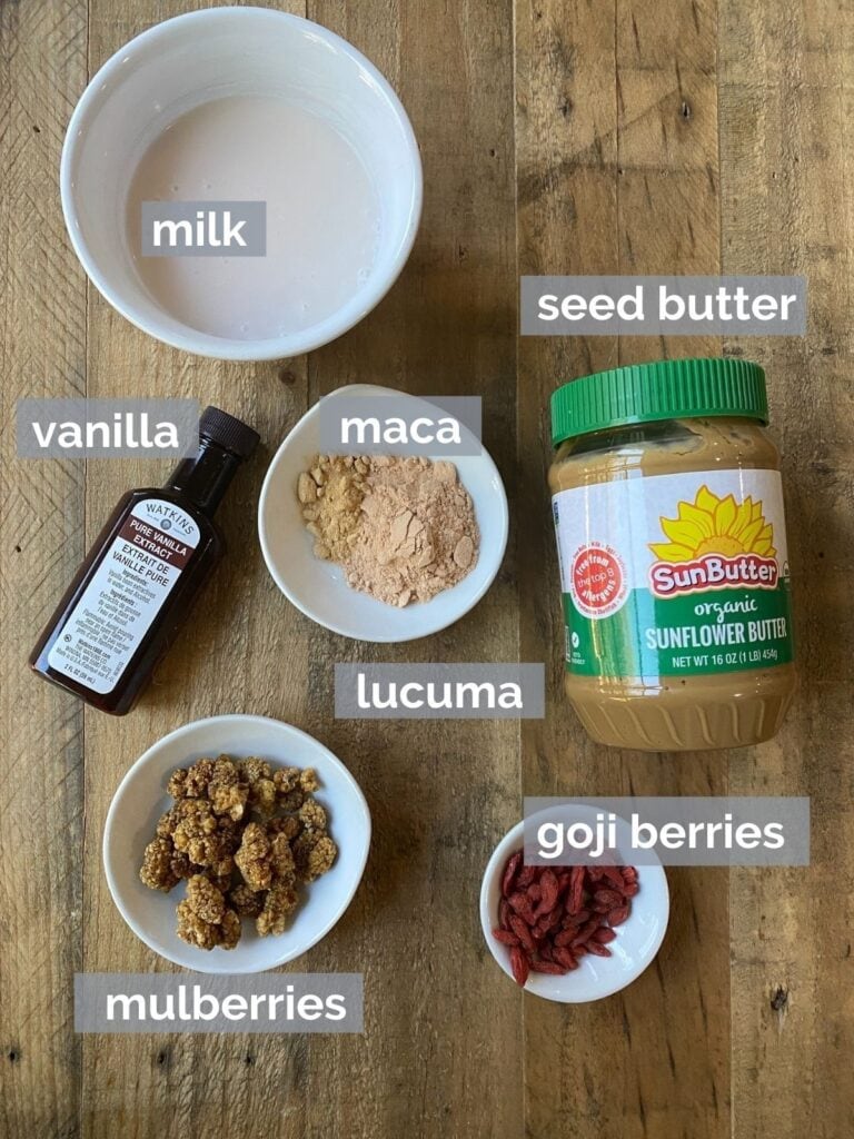 Maca, sunbutter, and other smoothie ingredients on a wood table