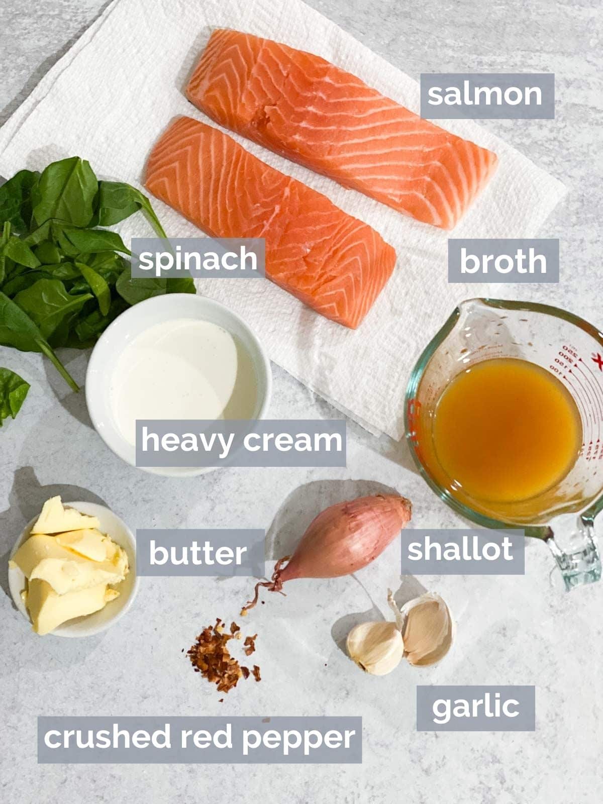 Salmon, spinach, broth, cream, butter, garlic, and shallot on a table