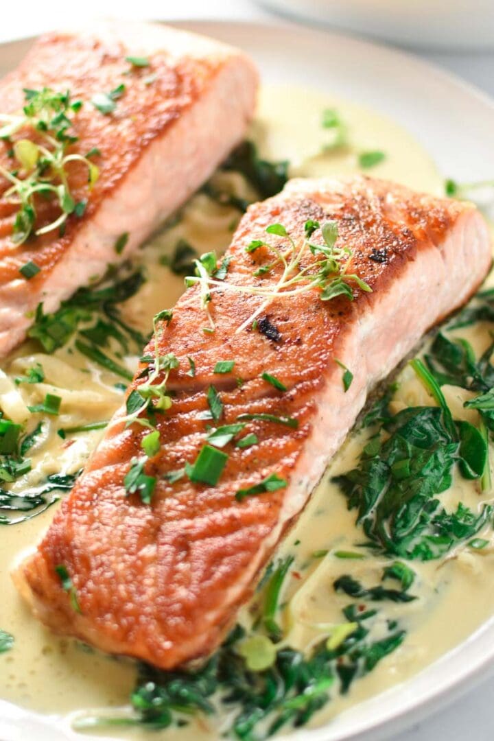 Two salmon with spinach cream sauce on a white plate
