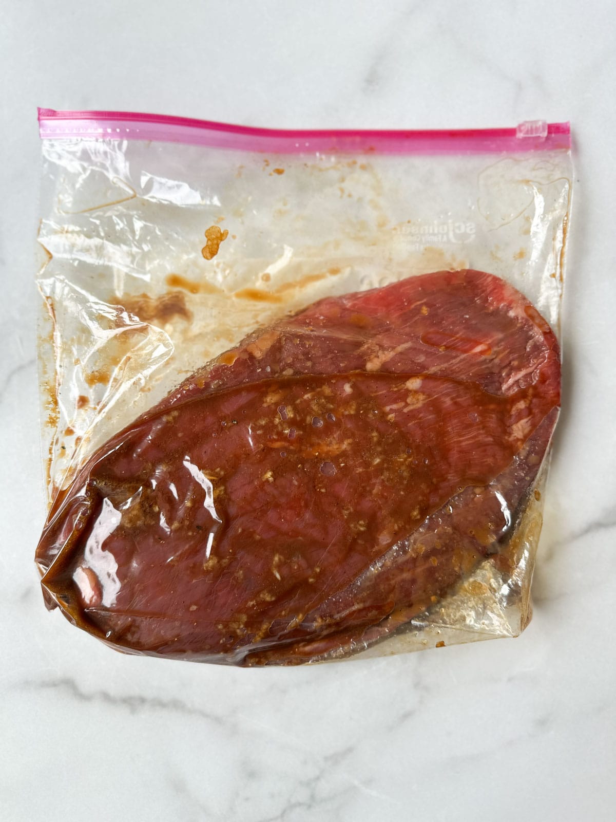 Flank steak being marinated in a bag.