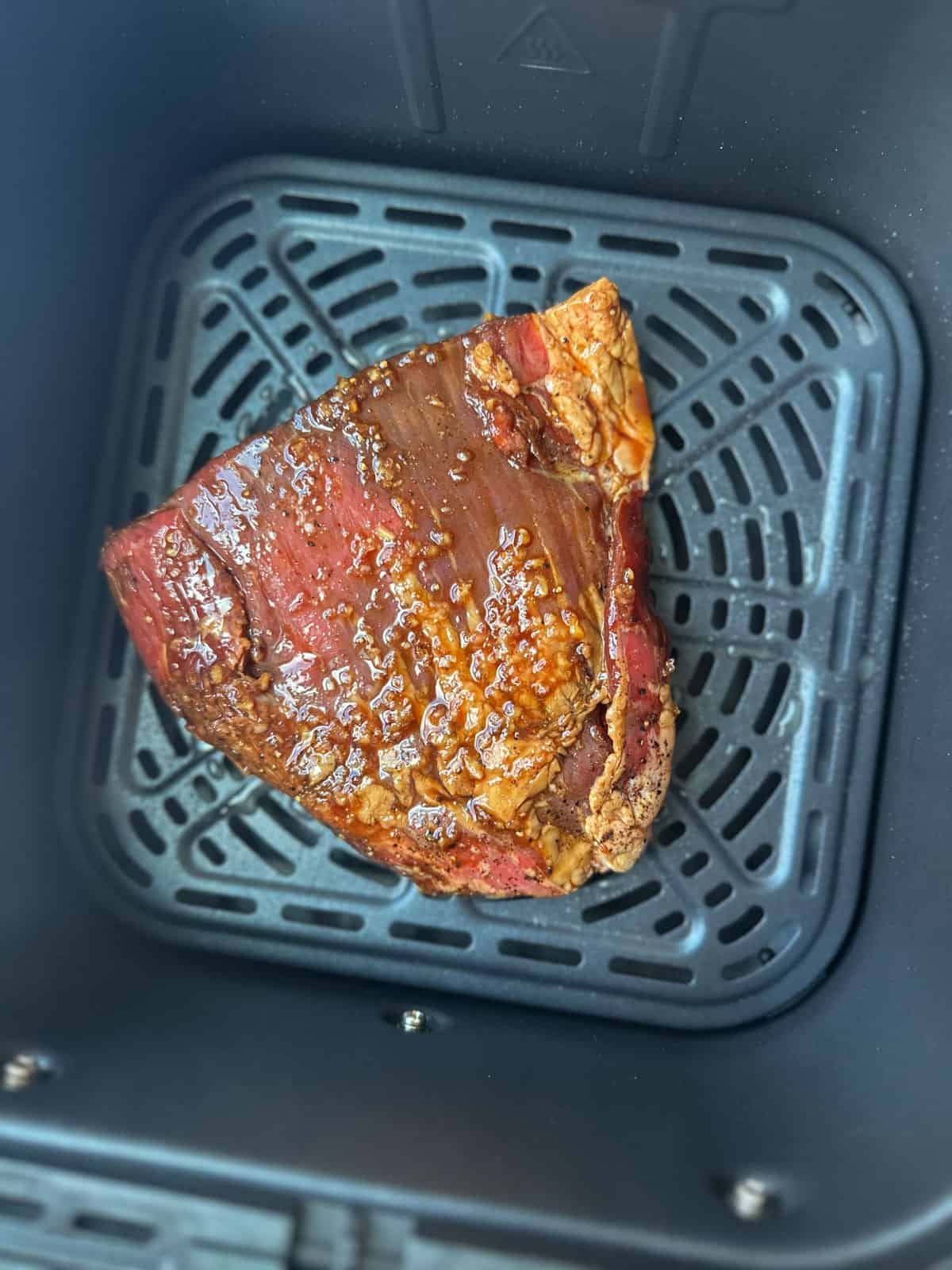 Marinated flank steak inside the air fryer basket.