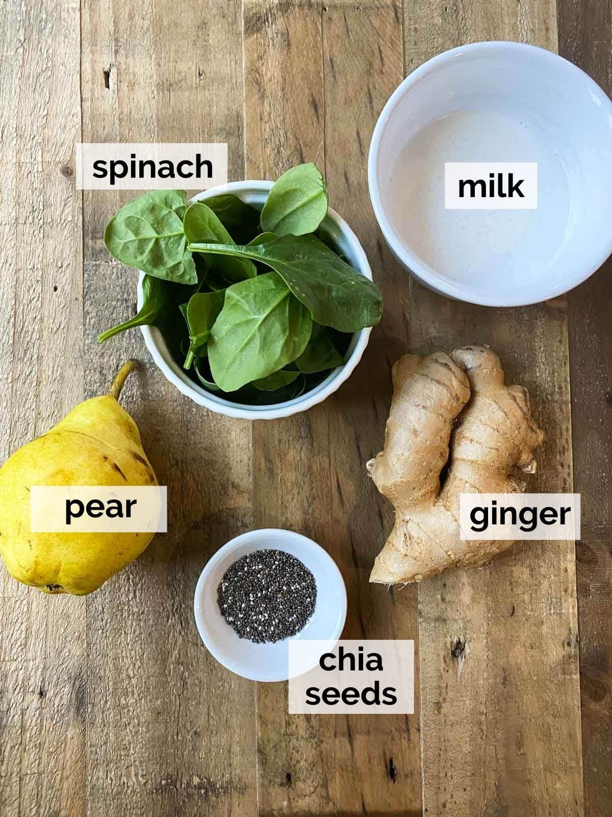 Ingredients for an anti-inflammatory smoothie including pears, greens, and chia seeds, on a wood table.