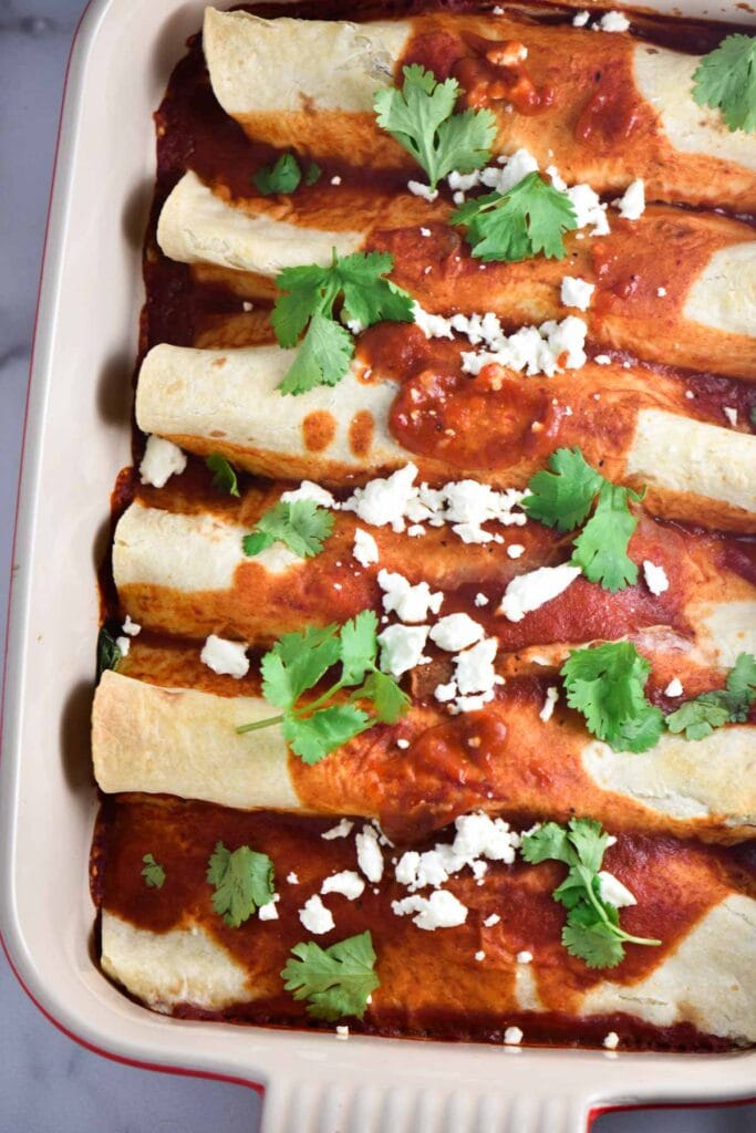 Healthy beef enchiladas in a baking dish topped with cheese and cilantro. 
