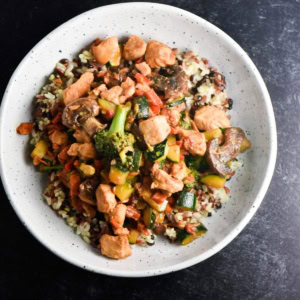 A bowl of soy free chicken stir fry with broccoli, squash, rice, and chicken.