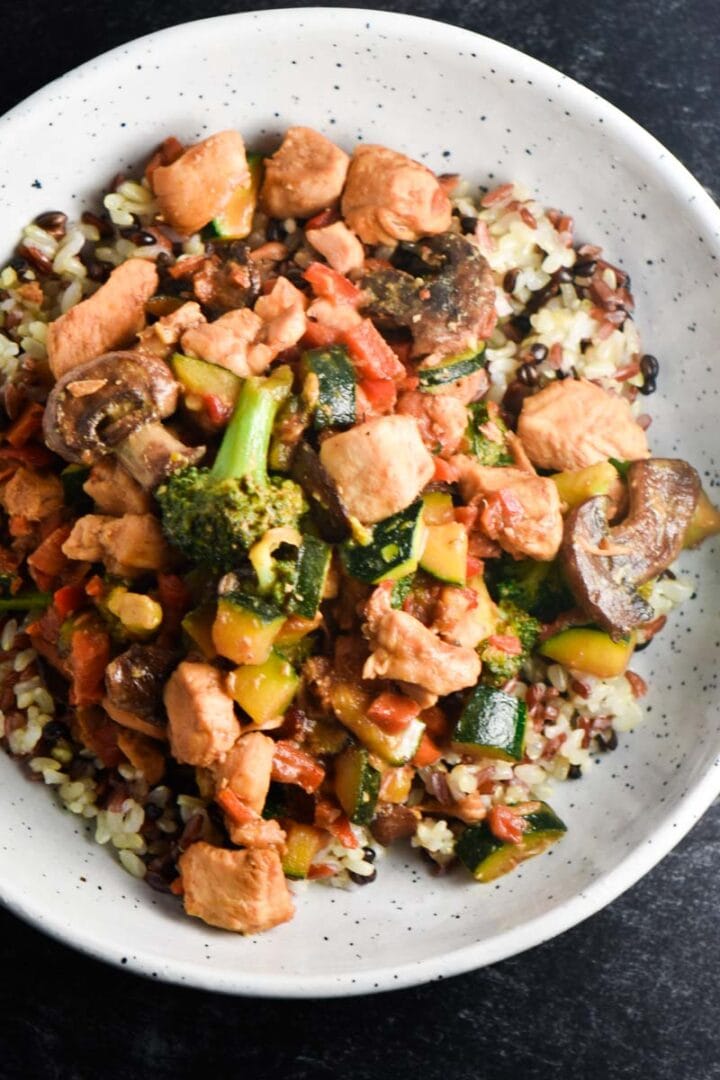 A bowl of soy free chicken stir fry with broccoli, squash, rice, and chicken.