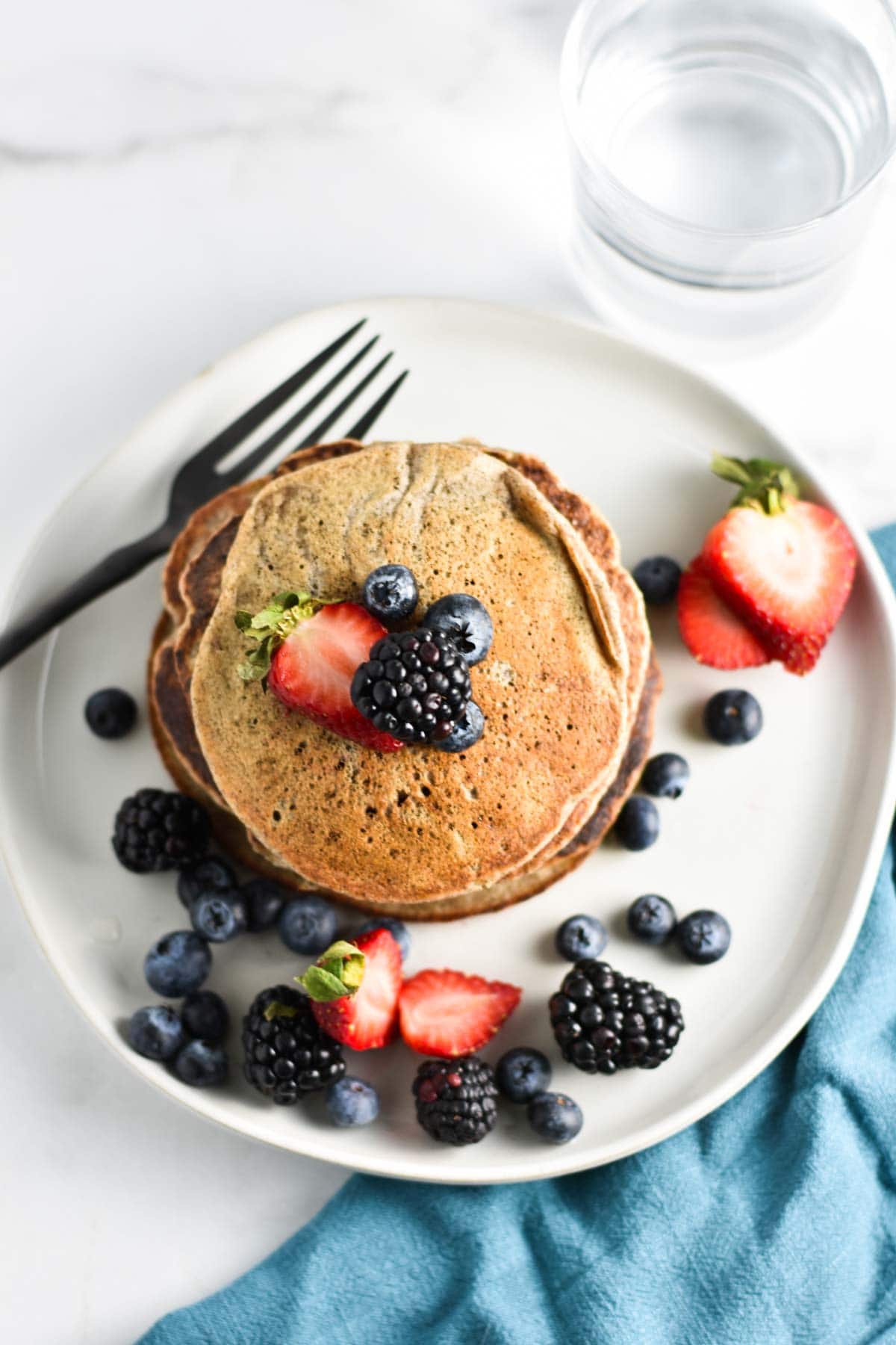 A stack of gluten free vegan pancakes with berries all around.