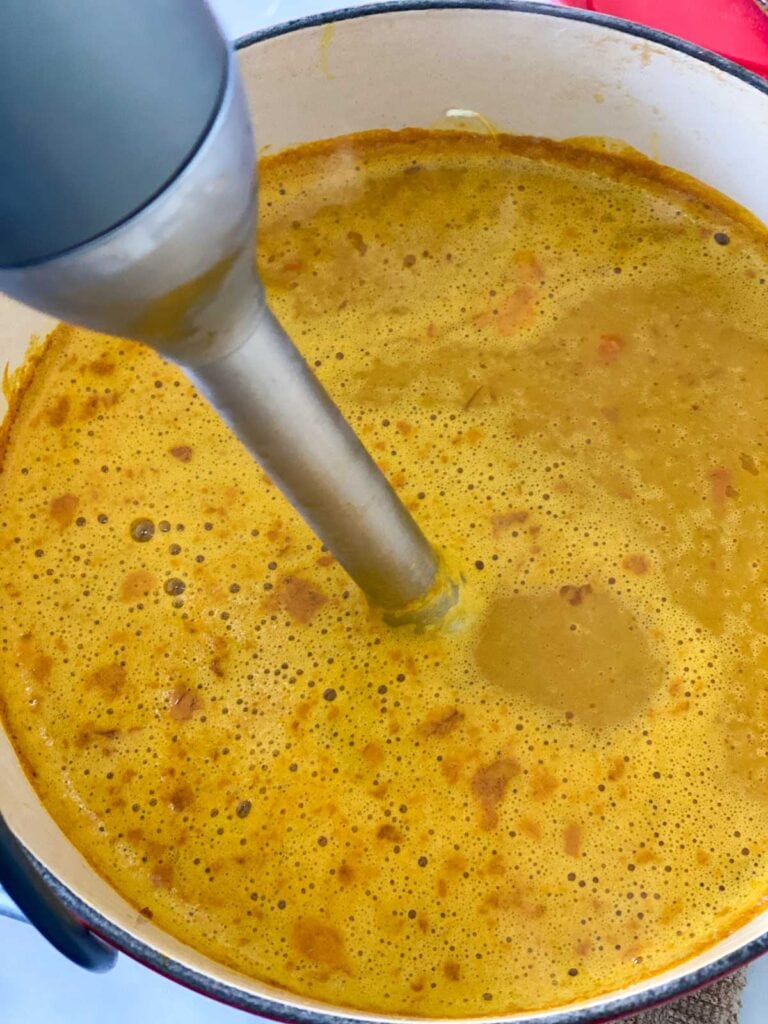 An immersion blender blending soup.