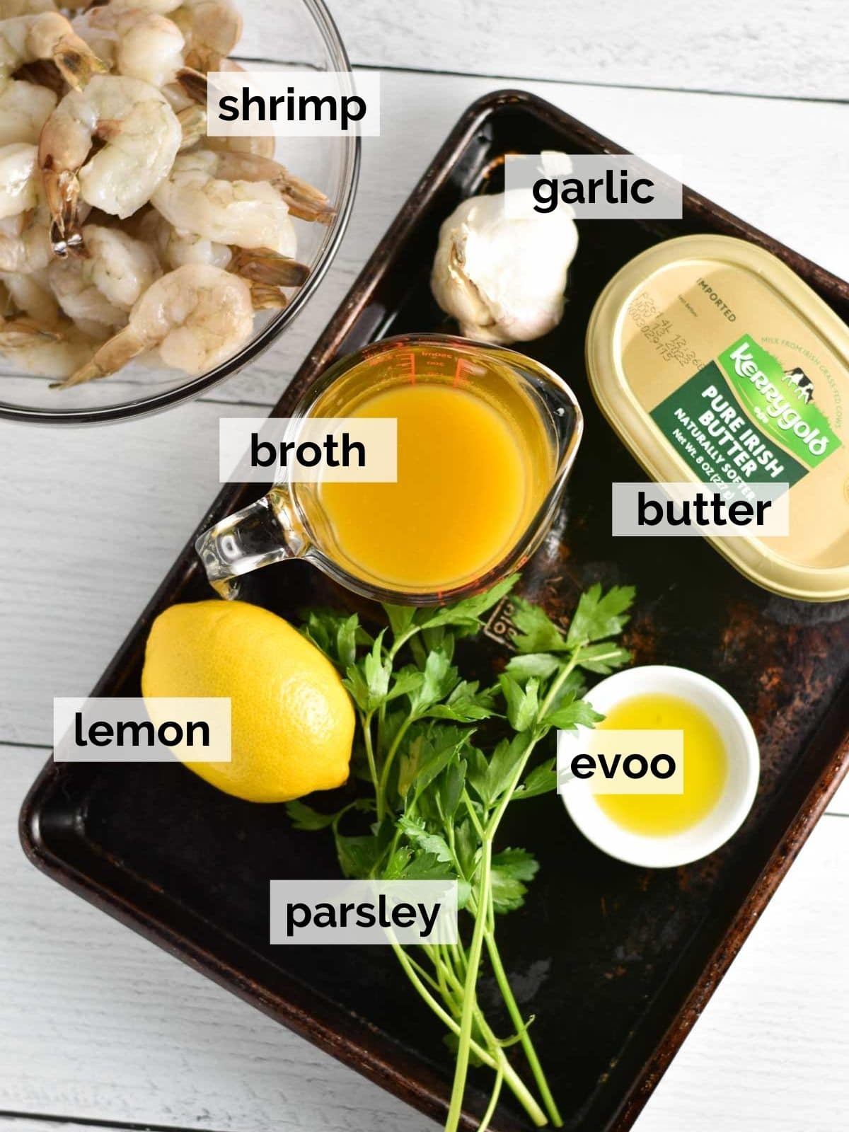 Shrimp, broth, butter, olive oil, garlic, and lemon on a sheet pan.