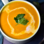 Sweet potato and red pepper soup in a green cup.