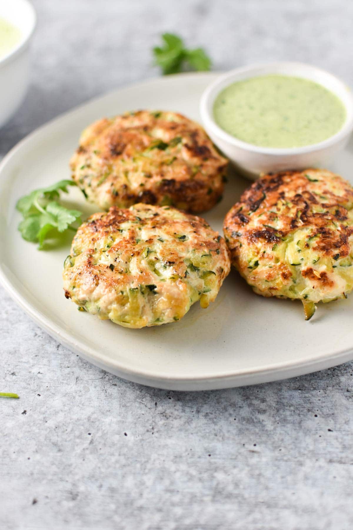 Zucchini chicken poppers on a plate next to a dipping sauce.