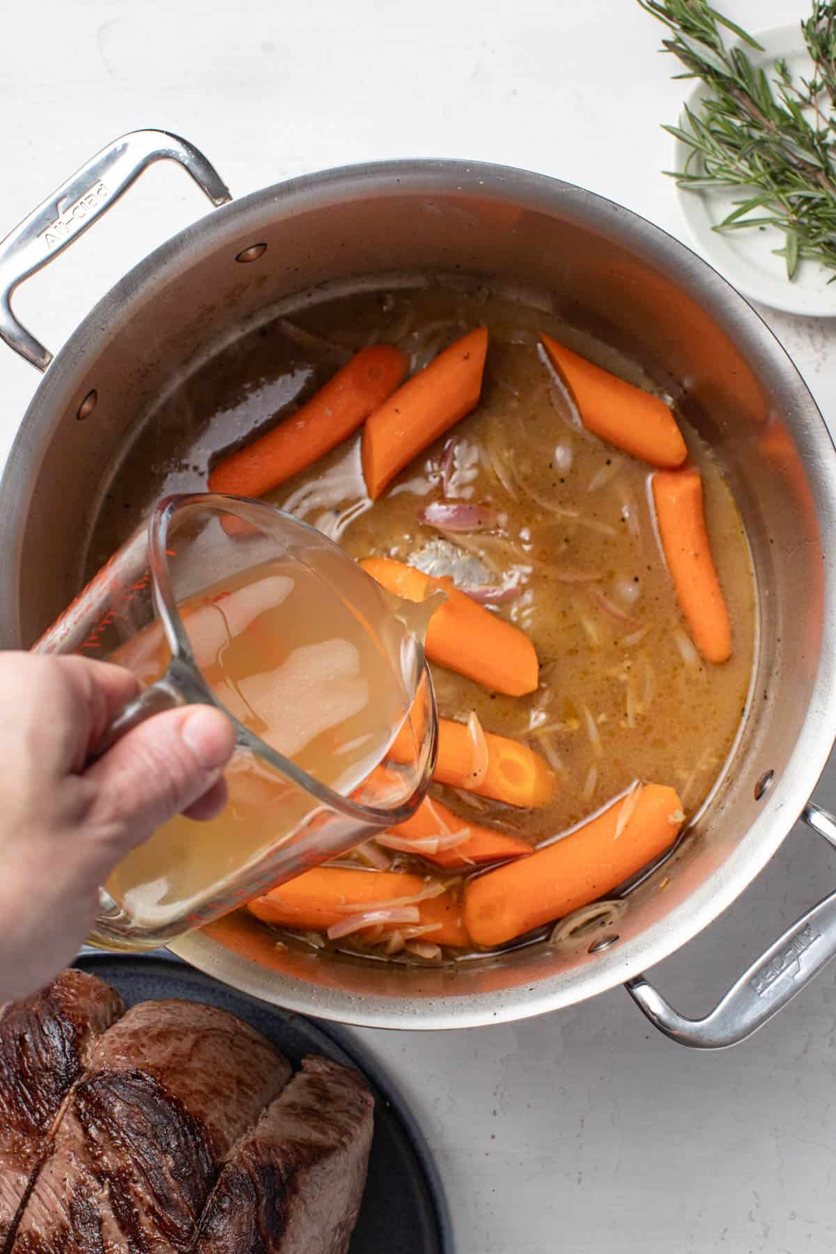 Adding apple juice to the dutch oven.