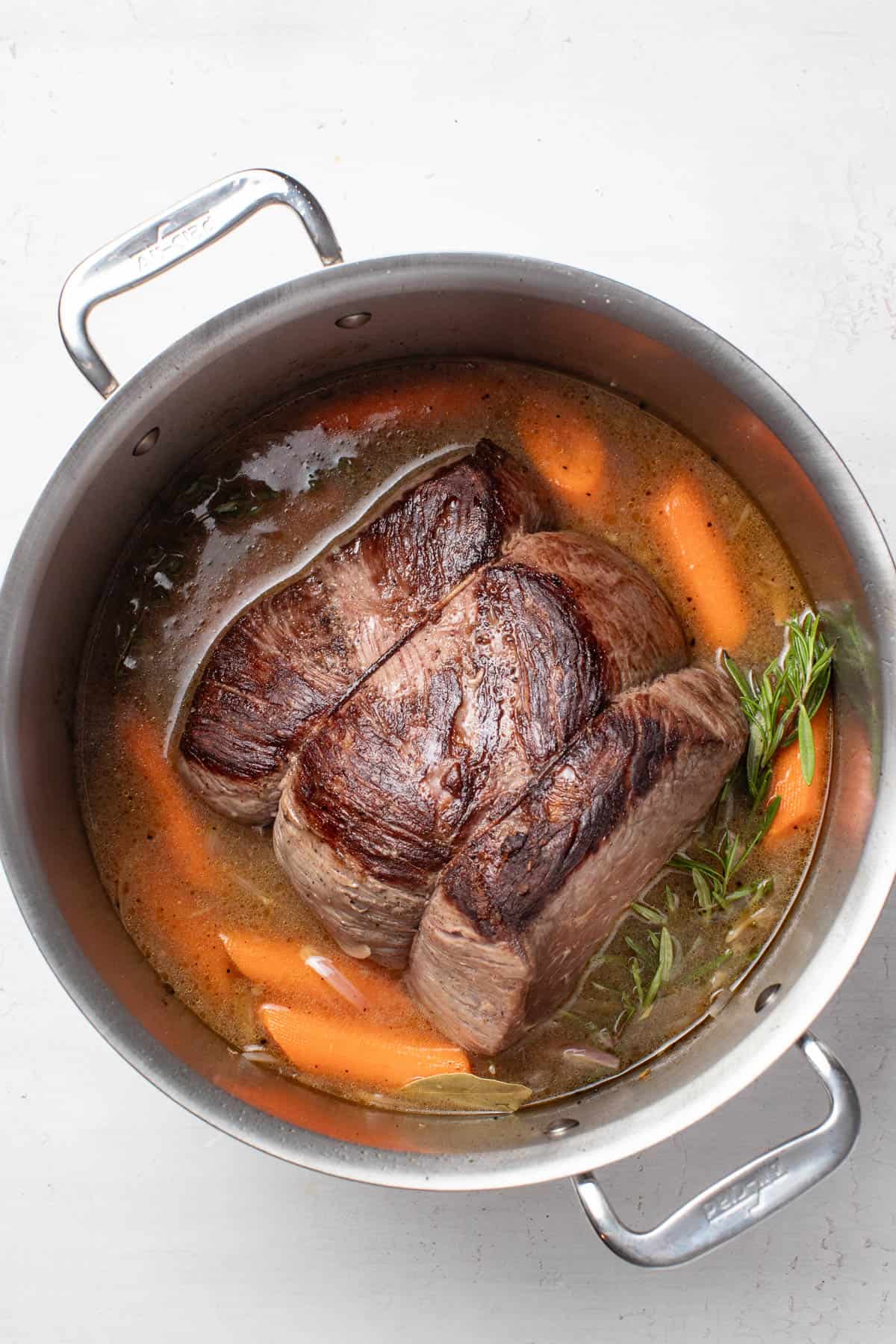 Adding the broth and apple jucie to the dutch oevn before cooking.