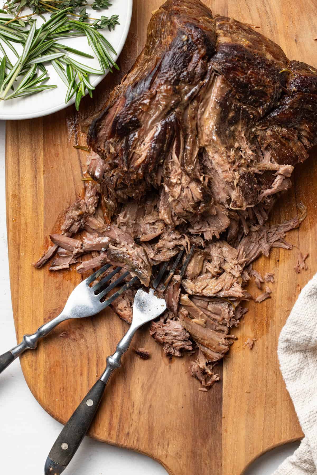 Shredding pot roast on a cutting board.