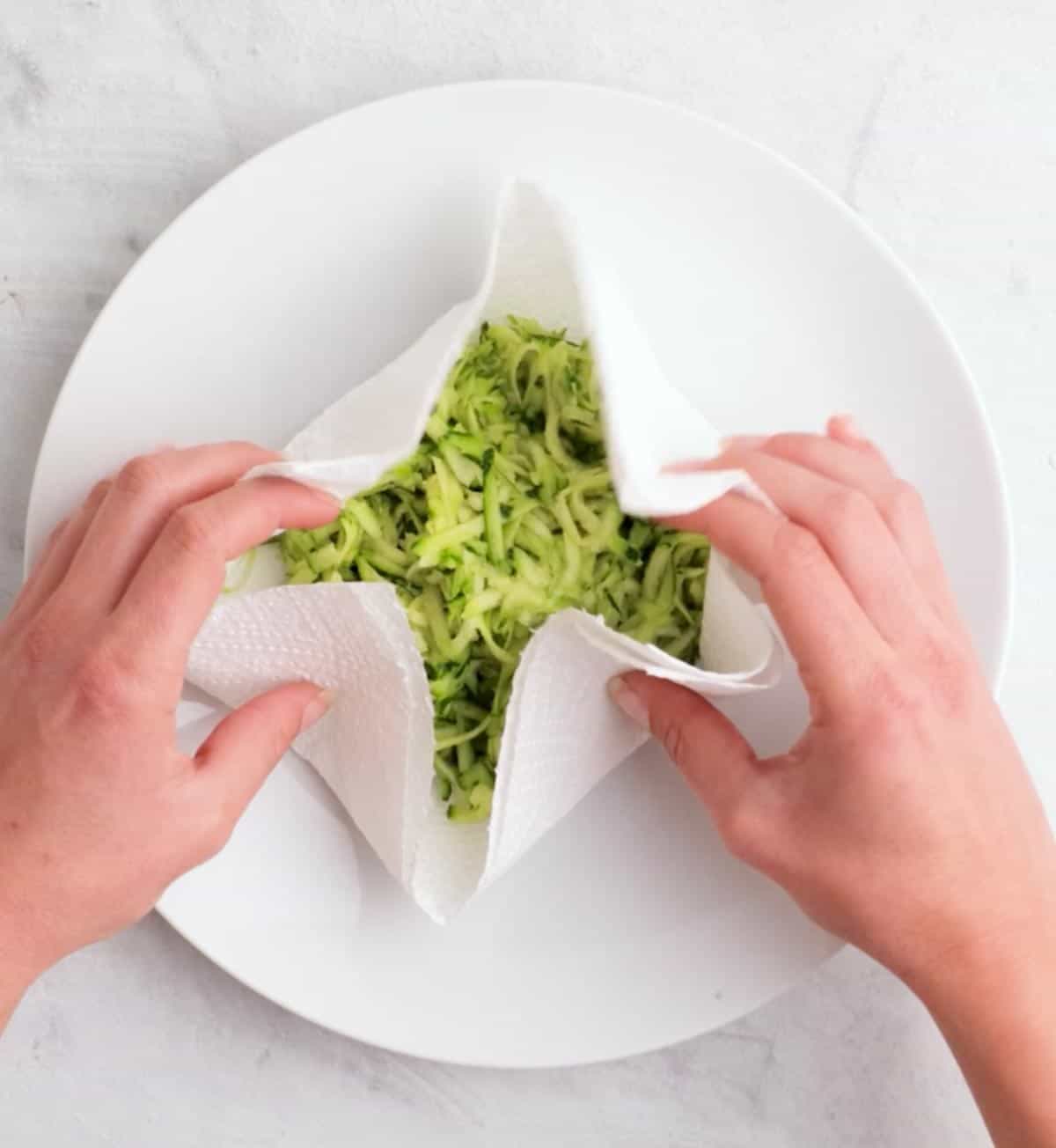 Wrapping shredded zucchini up in a towel to drain the excess liquid.