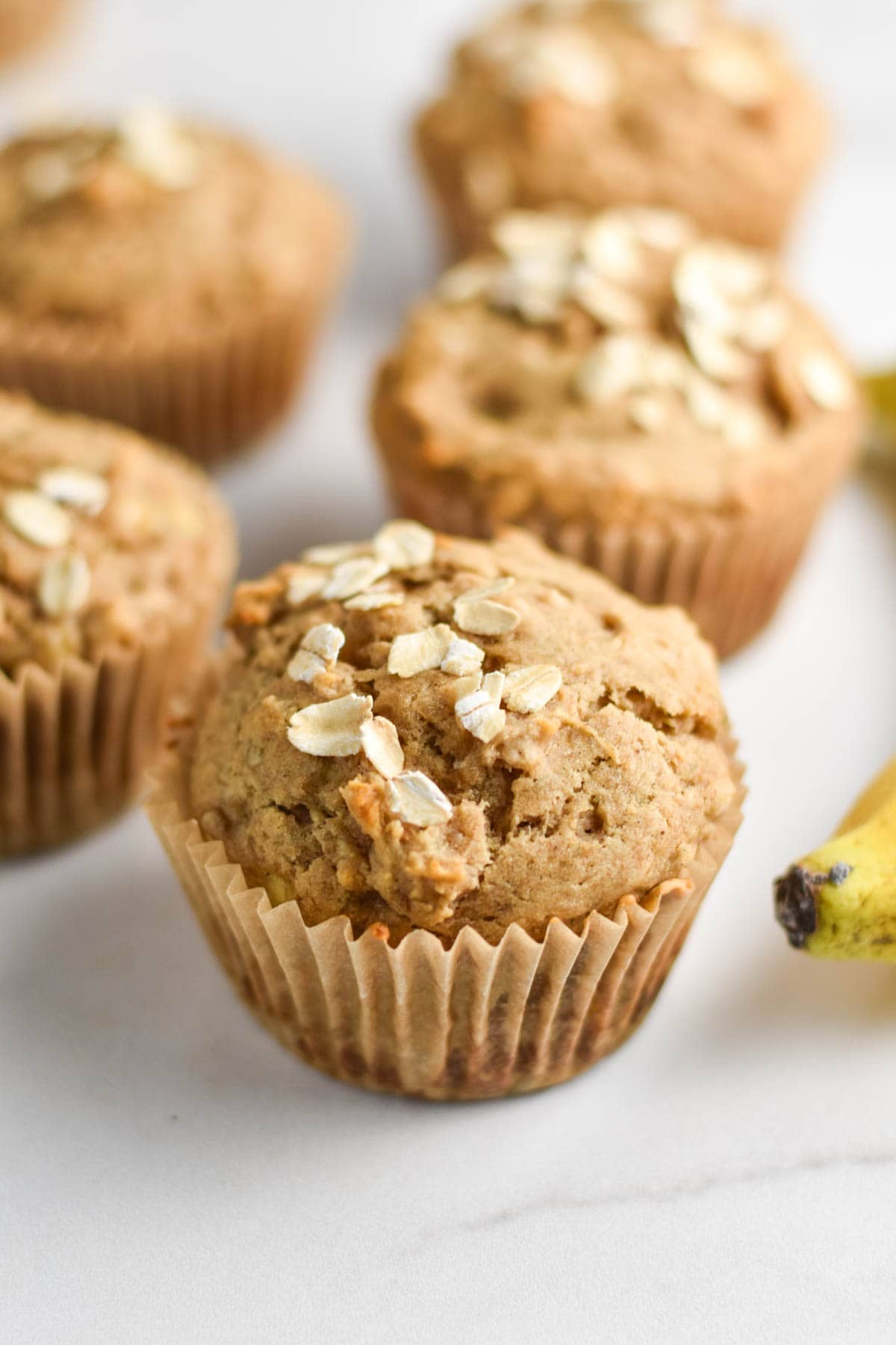 Muffins topped with oats next to a banana.