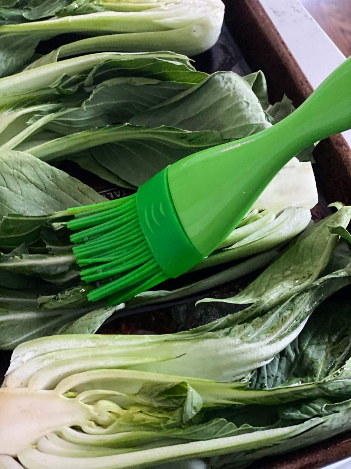 Brushing bok choy with toasted sesame oil.