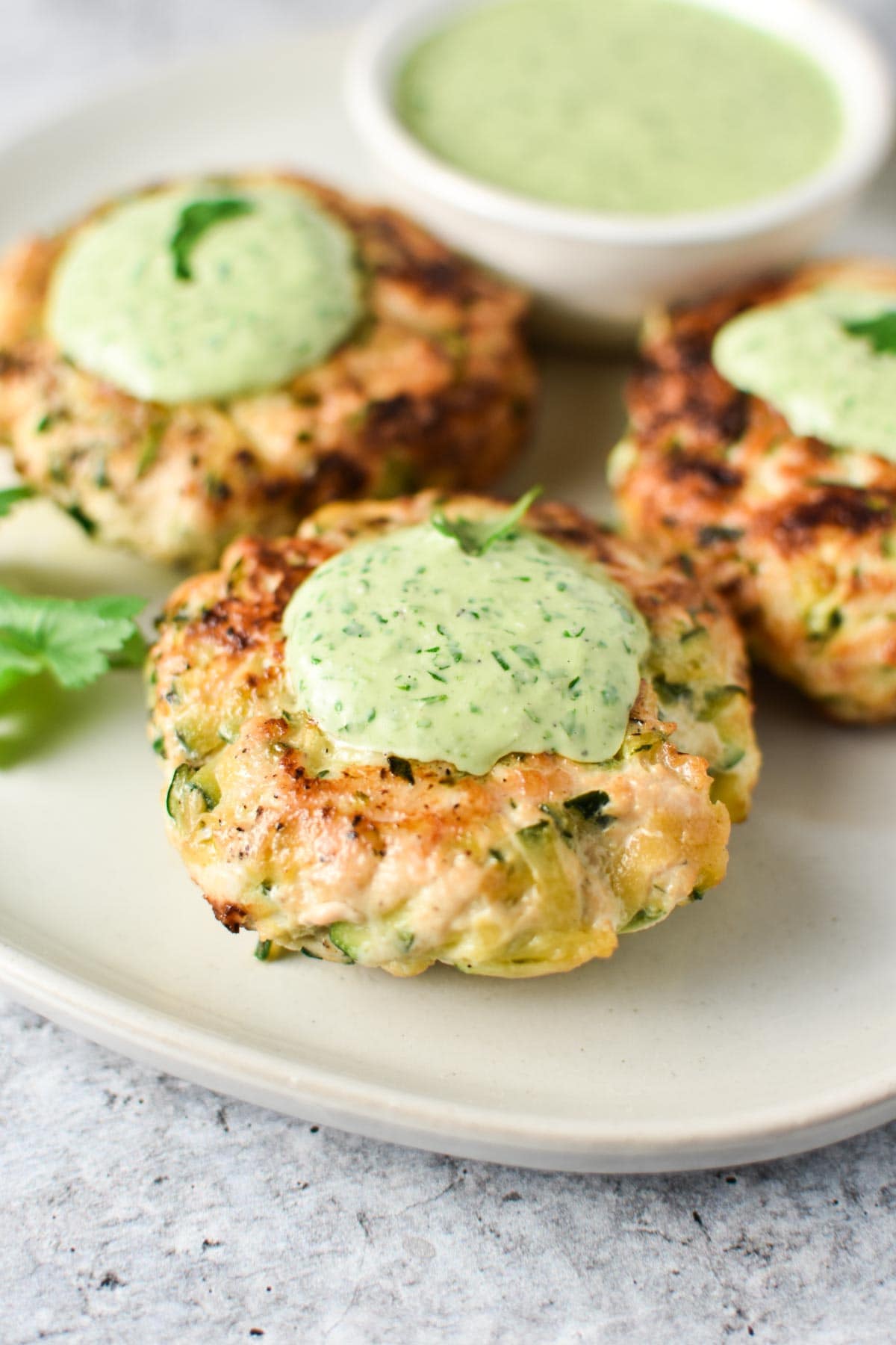 Three chicken zucchini poppers topped with a green cilantro sauce.