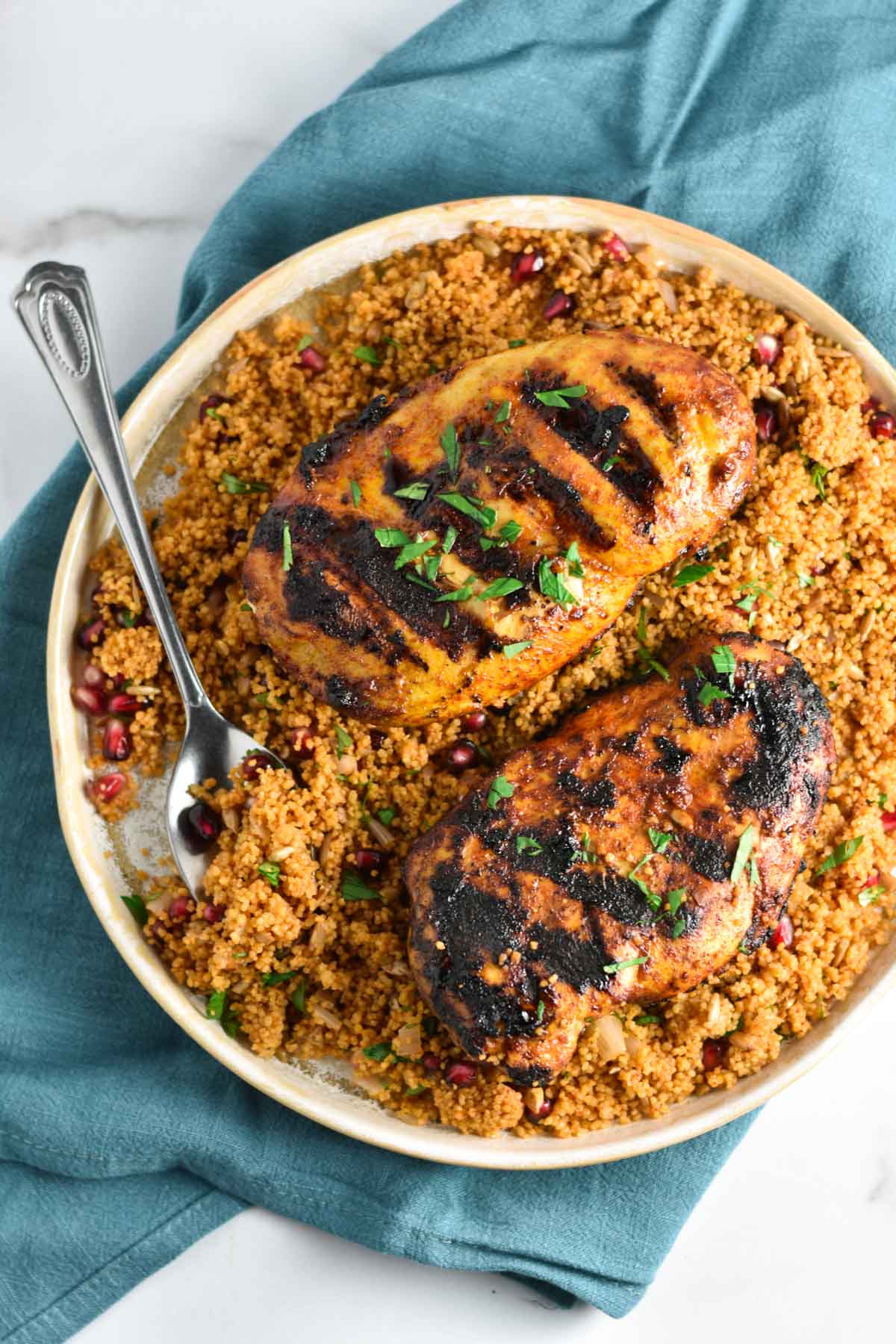 Chicken and couscous on a plate with a spoon.