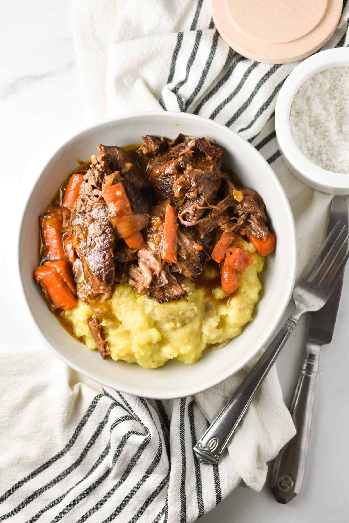 Pot roast with carrots in a bowl with mashed potatoes.