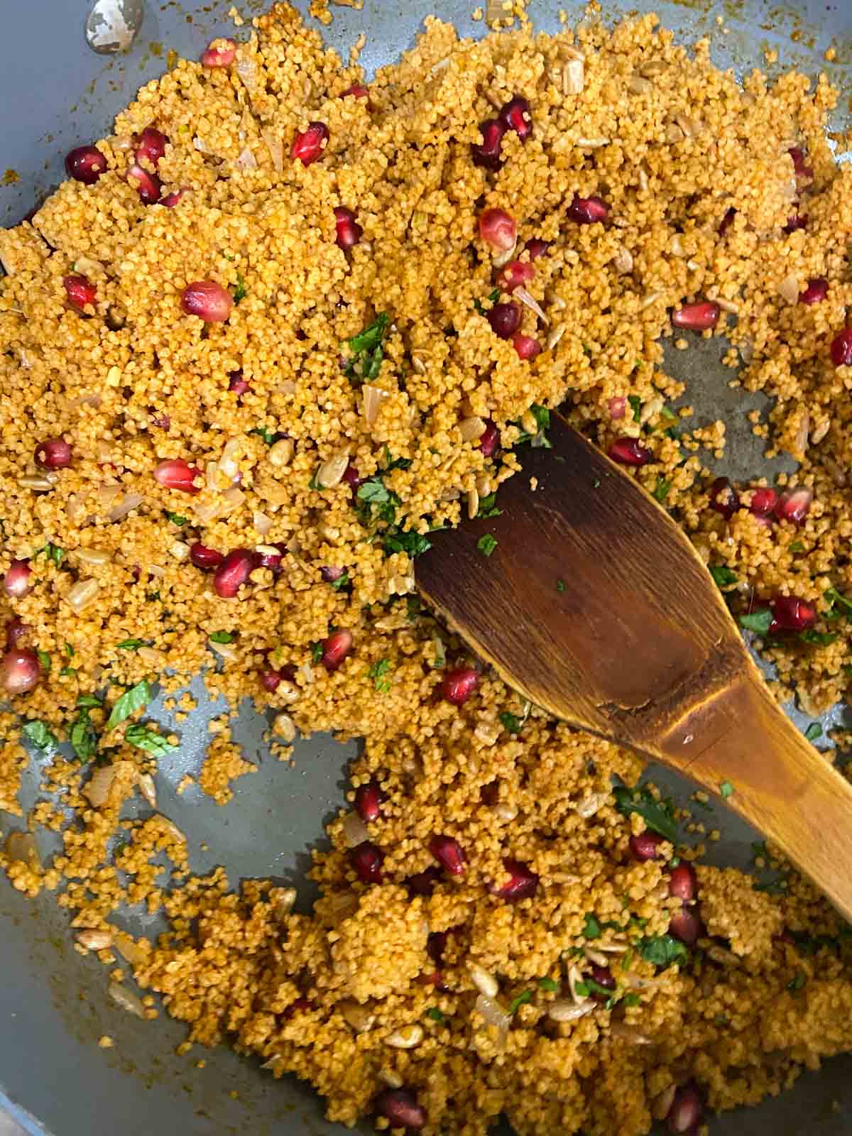 A spoon fluffing pomegranate couscous.