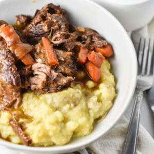 Pot roast in a bowl with mashed potatoes.