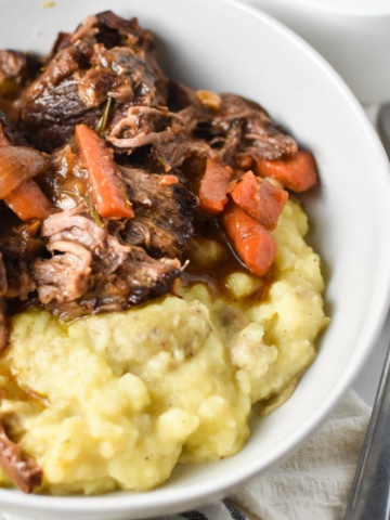 Pot roast in a bowl with mashed potatoes.