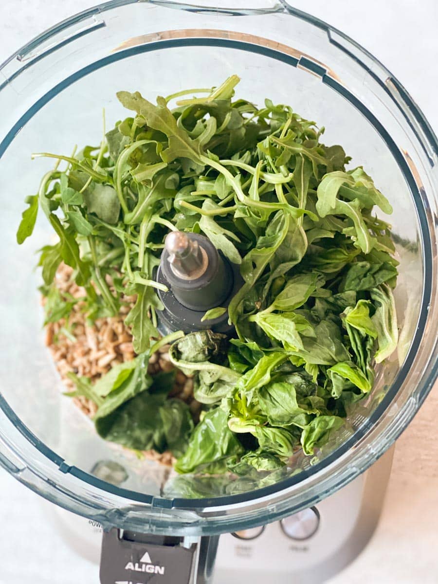 Arugula, sunflower seeds, basil, and garlic in a food processor.