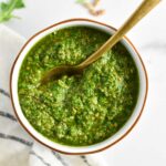 A spoon dipping into bright green sunflower seed pesto.
