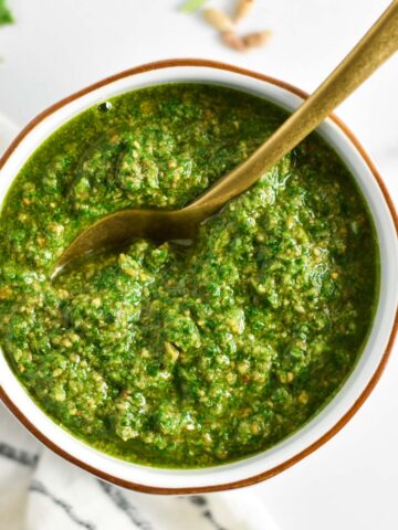 A spoon dipping into bright green sunflower seed pesto.