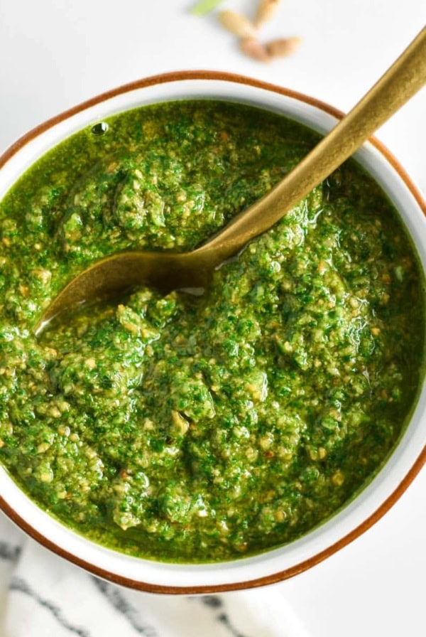 A spoon dipping into bright green sunflower seed pesto.