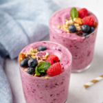 Two pink smoothies topped with berries.