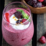 A cherry smoothie with fruit on top.