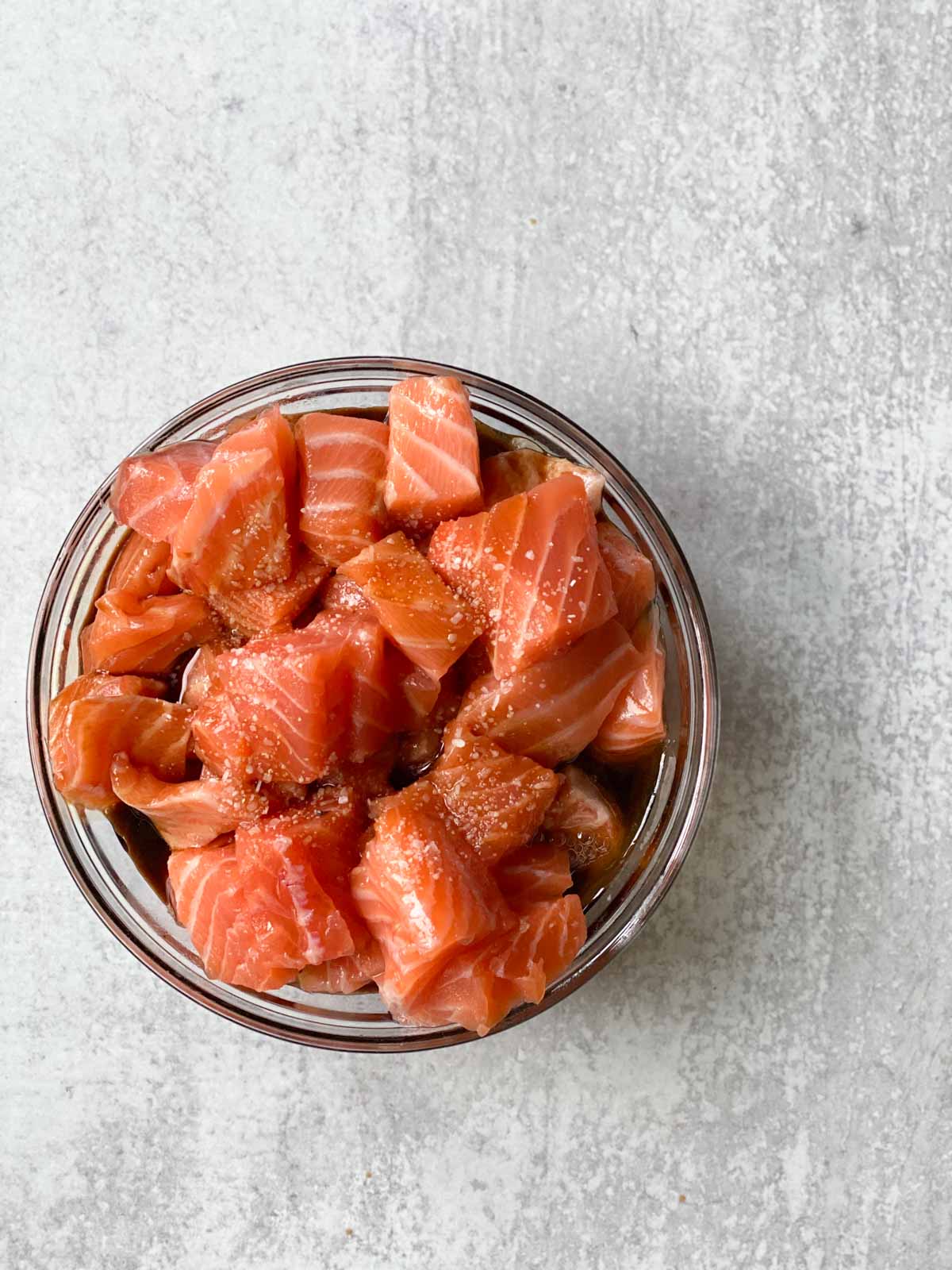 A bowl of salmon marinating in sauce.