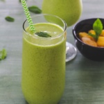 A green smoothie with a mint leaf.