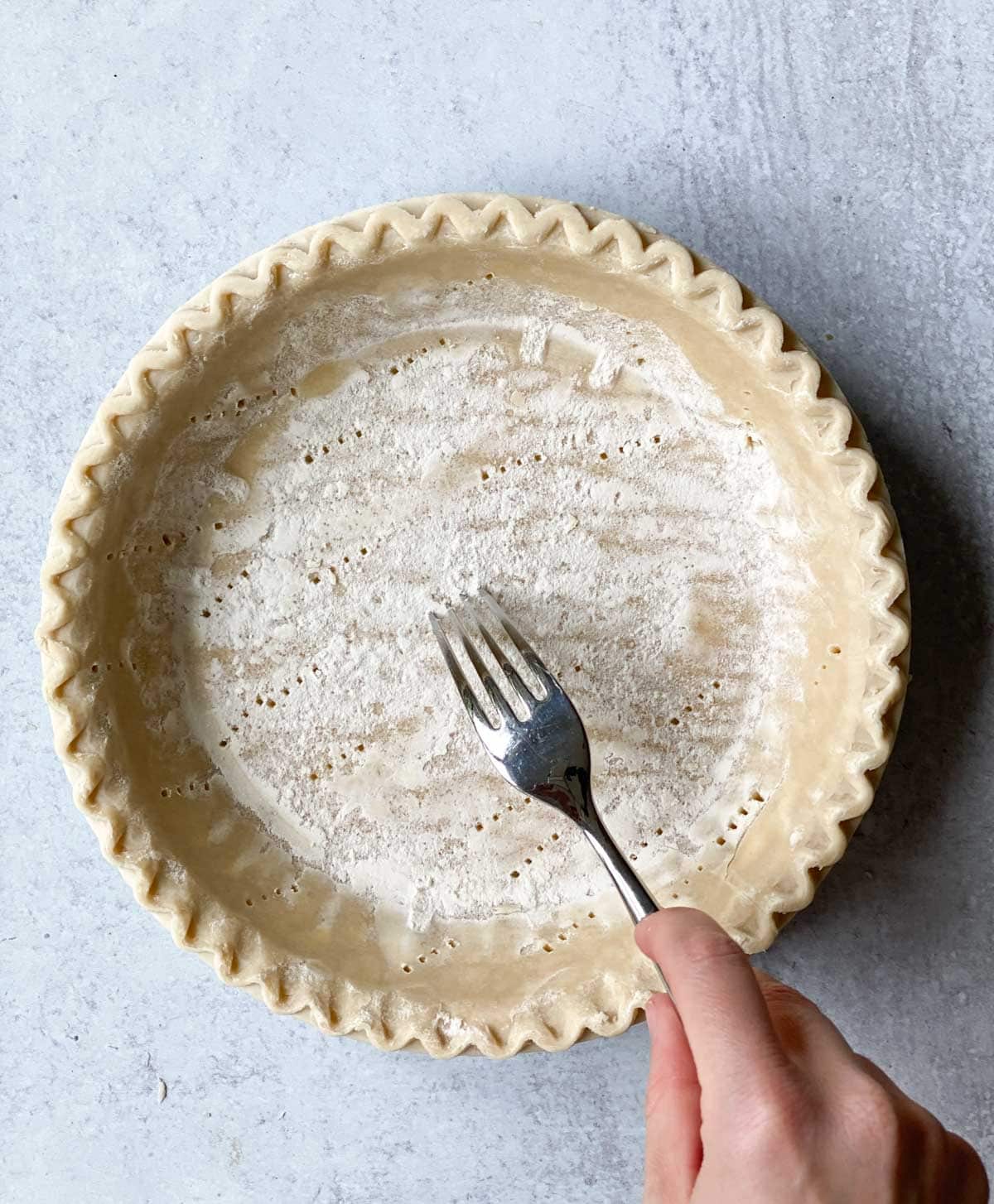 Poking a pie crust with a fork.