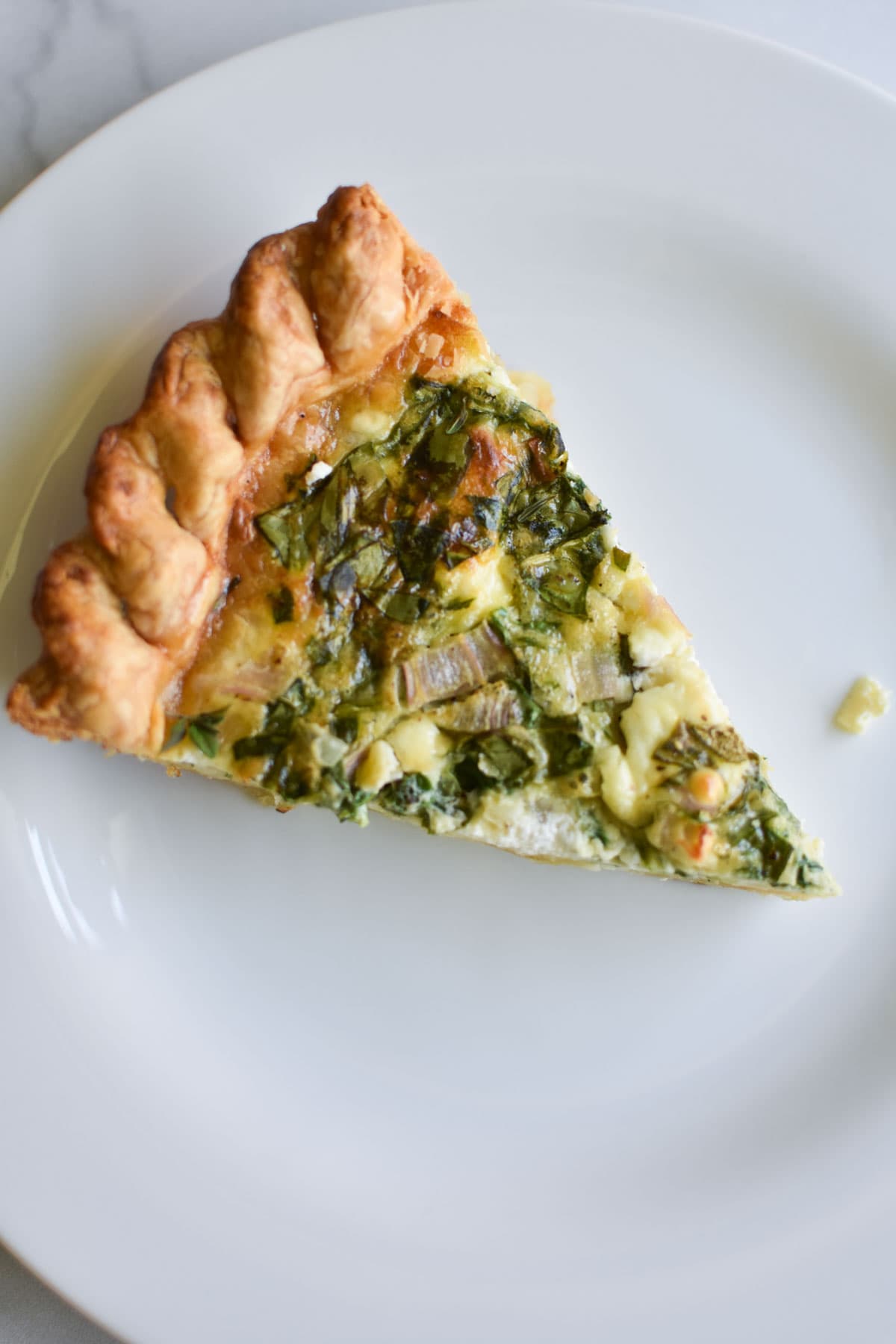 A slice of quiche on a plate.