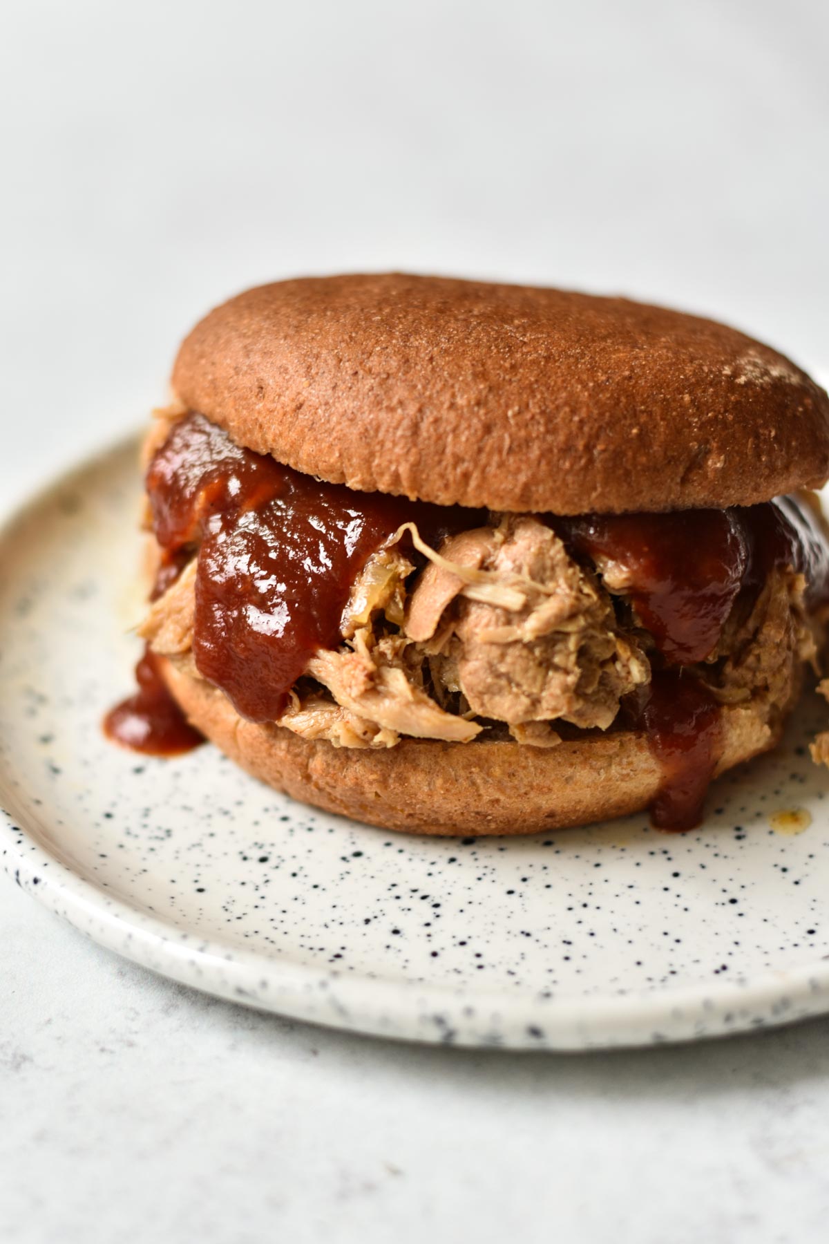 Slow cooker pork shoulder sandwich with sauce.