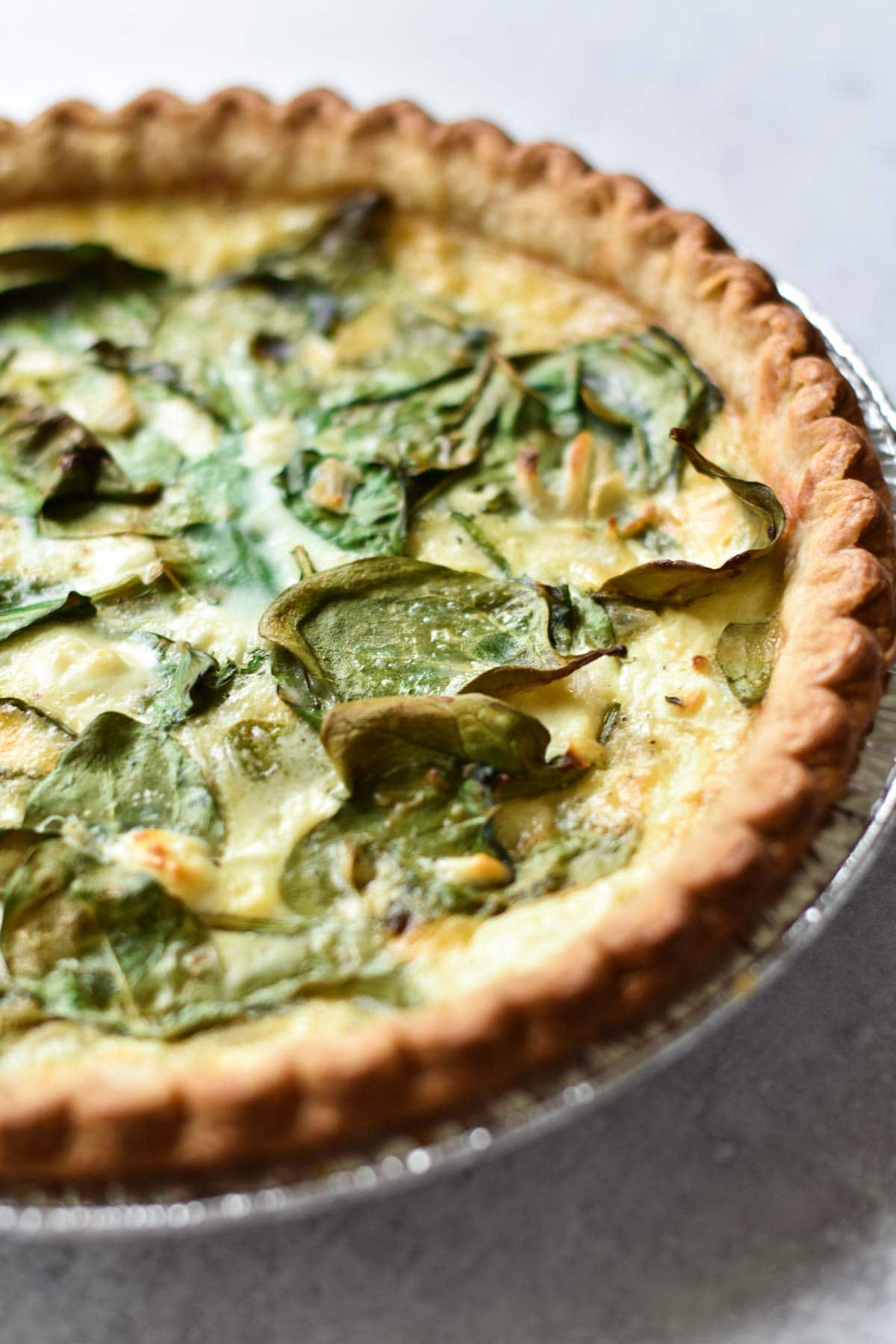 A side shot of spinach on top of quiche.