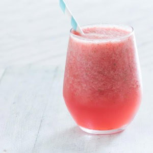 A pink watermelon smoothie on a table.