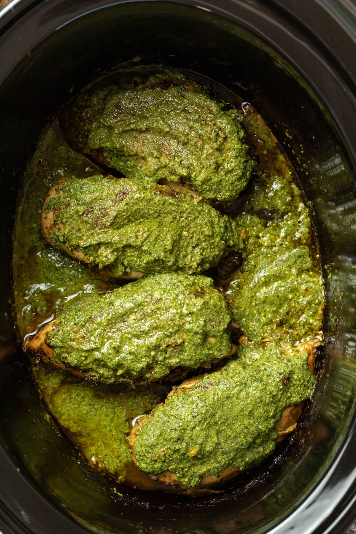 Adding more pesto to the top of the chicken breasts to restore the bright green color.