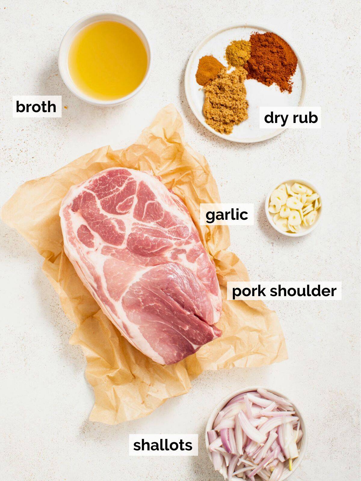 Boneless pork shoulder on a table with a dry rub and shallots.