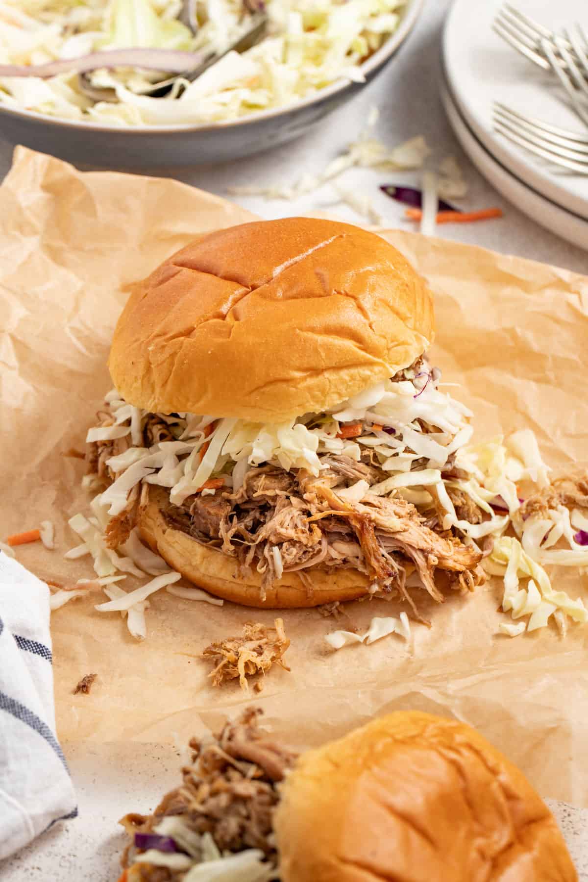 Shredded pulled pork sandwich from the pork shoulder topped with slaw in a bun.