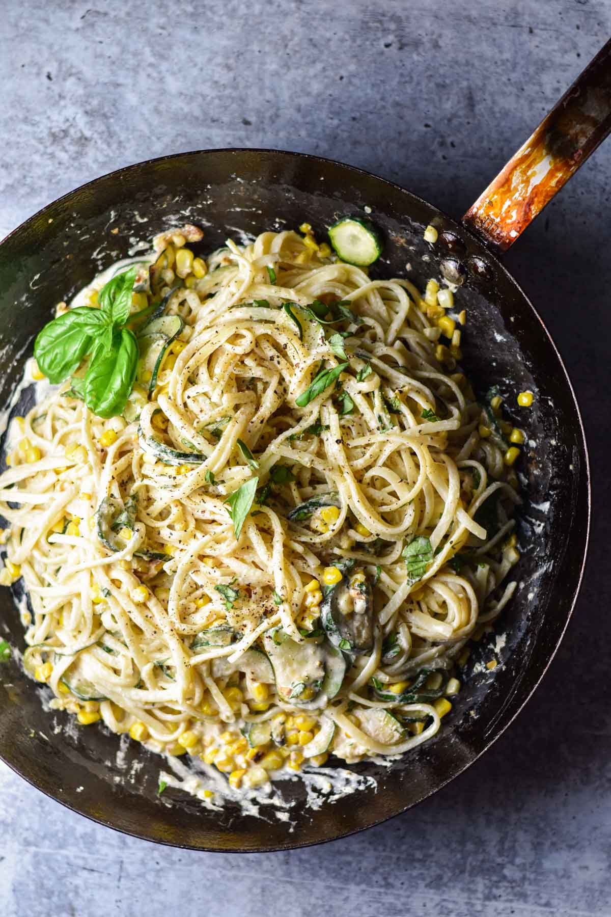 A large pan filled with pasta and basil.